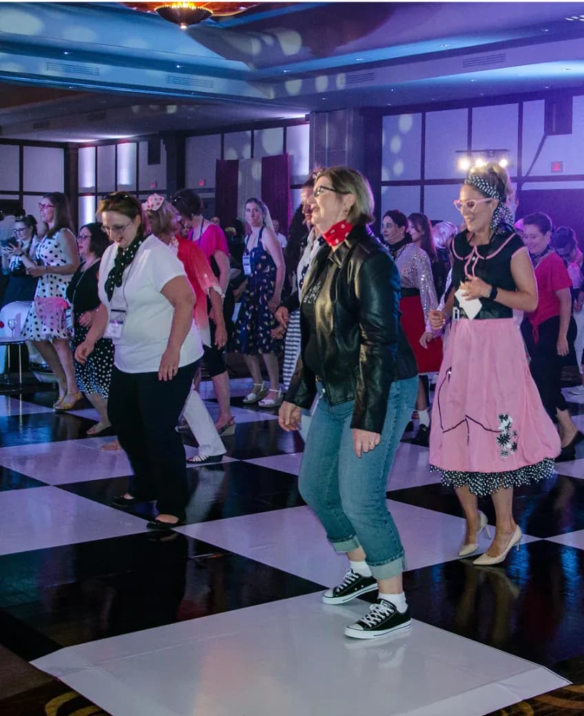 Guests in 1950s outfits dancing on a black-and-white checkered floor